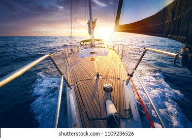 Sonnenuntergang auf dem Segelboot-Deck während der Fahrt / Segeln auf geöffnetem Meer. Yacht mit vollen Segel am Ende des windigen Tages. Segelthema - Hintergrund.