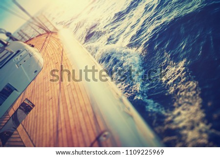 Sunset at the Sailboat deck while cruising / sailing at opened sea. Yacht with full sails up at the end of windy day. Sailing theme - background. Yachting background design.