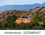 Sunset in Santa Fe, New Mexico mountains in Tesuque community neighborhood with sunlight on house home with green plants and shrubs and dark blue sky on high desert