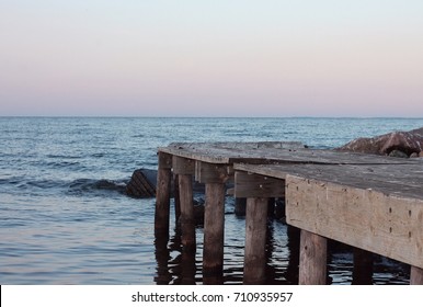 Sunset Scene Of A Dock, Rocks, Water, And Sky On A Lake In Northern Minnesota Outside The Lake-house Family Cabin. 