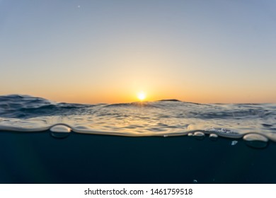 Sunset at sea level under waves