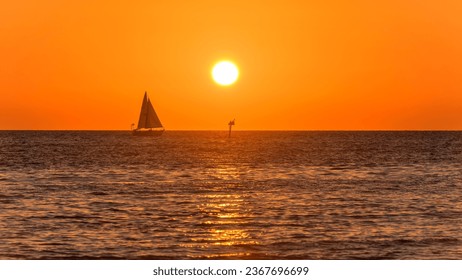 Sunset at Sea - A small sailboat sailing in front of setting sun and orange sky on a calm Autumn evening. Clearwater, Florida, USA. - Powered by Shutterstock