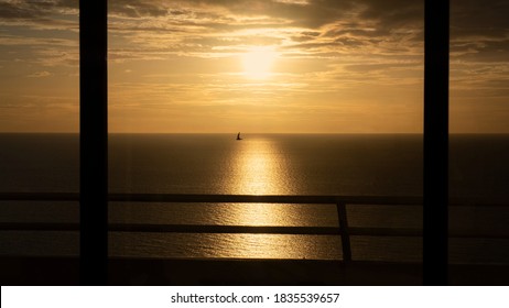 Sunset and sea view from room with flying bird through an open window and terrace fence. Summer holiday nature golden sky concept 