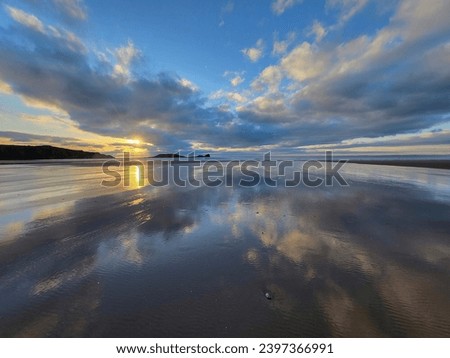 Sunset seascape at Rhossili Bay and Worm's Head in South Wales at twilight. The bay is three miles long and has been voted Wales' Best Beach. Blue hour in wide angle with copy space.