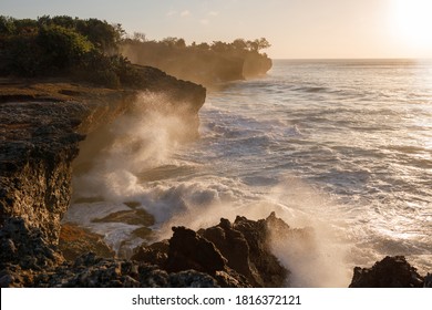 Sunset seascape with rocky beach and crashing waves