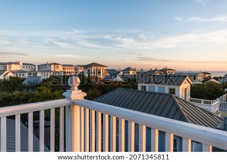 Sunset in Seaside, Florida Gulf of Mexico, view from wooden rooftop terrace balcony building with houses cityscape and white railing balustrade ball top finial