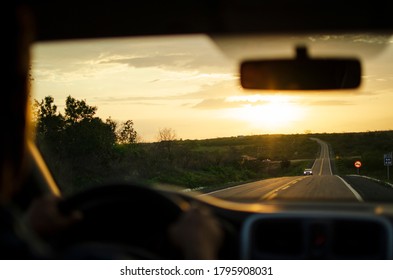 a sunset seen from inside the car on the road