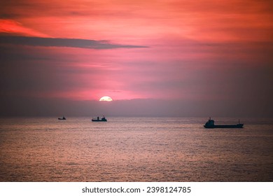 The sunset seen on the seaside in southern Taiwan, the sky is full of red, and the sunlight shining on the fishing boats on the sea is like gold foil.
