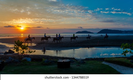 At sunset several tourists walking on horseback in Jaco Beach. Costa Rica, nature paradise - Powered by Shutterstock