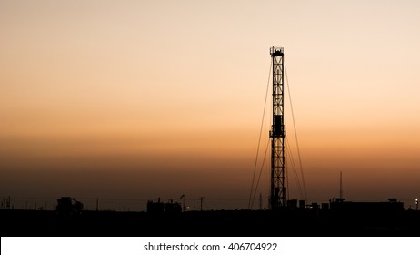 Sunset and silhouette of drilling rig in oilfield 