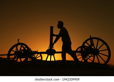 Sunset And Silhouette Of Horse Carriage Mechanic.