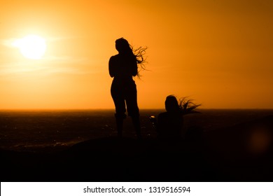 Sunset Silhouette: Same Sex Couple Of Girls At Sunset In Camps Bay Tidal Pool, Cape Town, South Africa