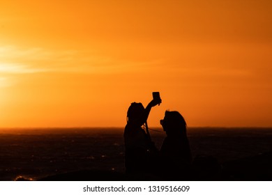 Sunset Silhouette: Same Sex Couple Of Girls At Sunset In Camps Bay Tidal Pool, Cape Town, South Africa