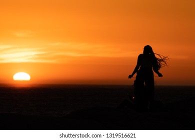 Sunset Silhouette: Same Sex Couple Of Girls At Sunset In Camps Bay Tidal Pool, Cape Town, South Africa