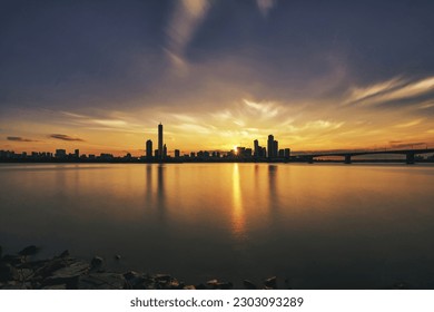 Sunset and silhouette view of 63 Building and high rise buildings of financial district with Wonhyo Bridge on Han River at Yeouido near Yeongdeungpo-gu, Seoul, South Korea
