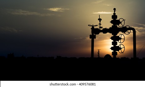 Sunset and silhouette of well head in the oilfield 