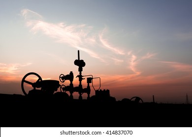 Sunset and Silhouette of wellhead controls in oilfield 