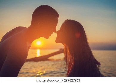 Sunset Silhouette Of Young Couple In Love At Beach