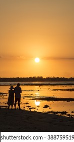 Sunset Silhouette Of Young Couple In Love Hugging At Beach