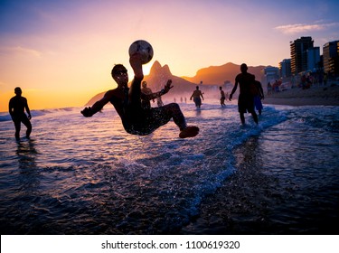 Sunset Silhouettes Playing Keepy-uppie Beach Football On The Sea Shore In Ipanema Beach Rio De Janeiro Brazil