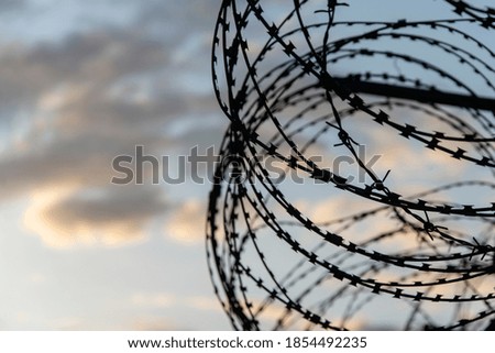 Similar – Fence with a barbed