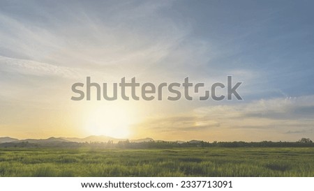 Sunset sky clouds in the evening with Orange sunlight over Landscape green field and mountain