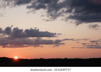 Sunset sky with dark clouds over the forest on the horizon