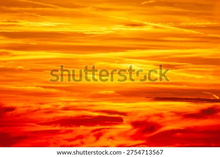 Sunset sky looking like a flame in bursting yellow, red and orange bright colors, on brushstroke clouds, suitable as natural abstract  background with copy space
