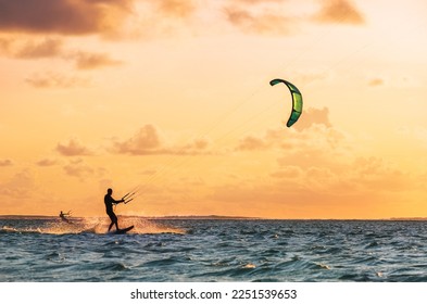 Sunset sky over the Indian Ocean bay with a two kiteboarders riding kiteboards with a green bright power kites. Active sport people and beauty in Nature concept image. Le Morne beach, Mauritius. - Powered by Shutterstock