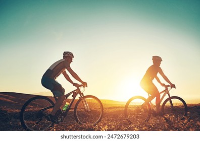 Sunset, sky and people on bicycle with adventure, race and exercise trail in nature together. Cycling, fitness and friends with mountain bike in evening for outdoor workout, blue sky and grass path - Powered by Shutterstock