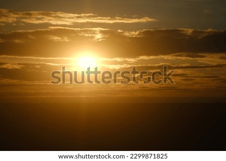 Sunset sky with red light of the setting sun. Evening clouds in the orange light of sunset rays