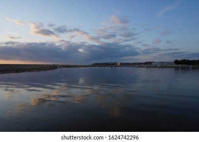 Sunset sky reflection in the water, clouds, sea shore.