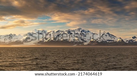 Sunset starts to develop over panorama of mountains and Mount Fairweather by Glacier Bay National Park in Alaska
