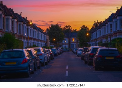 Sunset at a street of terraced houses with cars parked in resident bay around West Hampstead in London - Powered by Shutterstock