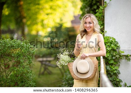 Sunset in summer.Rural life.A young woman with a basket,a bouquet of wildflowers and a hat standing in the background of the garden .Female portrait Life in the country.