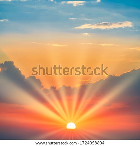 Sunset with sun rays and clouds on blue and orange dramatic sky