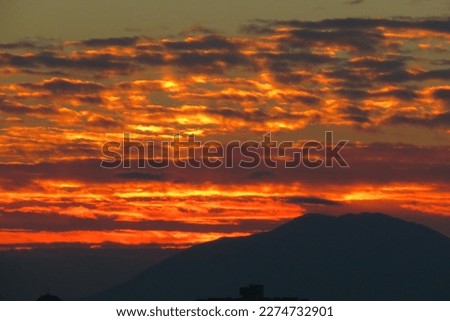 Sunset sunrise beautiful sun behind buildings and mountains sunset above city burning sky landscape sun and clouds contrast