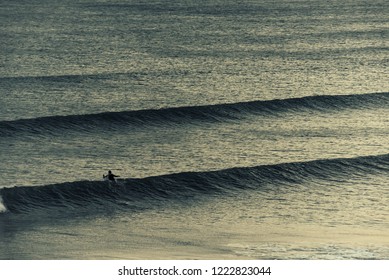 Sunset surfer chasing waves