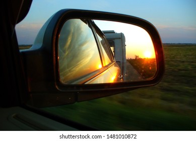 Sunset And Trailer Reflecting In The Car Rearview Mirror. Caravanning, Car Traveling, Summer Holidays Concept.