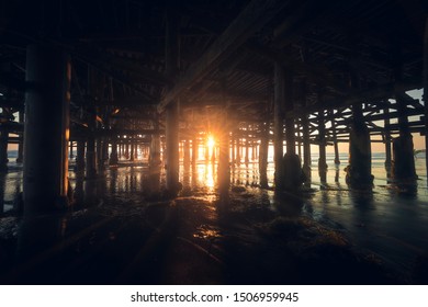 Sunset under a dock on the beach.