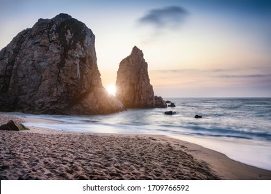 Sunset at Ursa Beach Sea stack, Portugal. Atlantic Ocean Foamy waves rolling to sandy beach. Holiday vacation landscape scene - Powered by Shutterstock