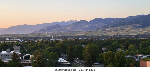 Sunset view of the Bridger Mountain Range rising above downtown Bozeman with neighborhoods and trees in the foreground in southwest Montana.