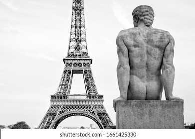Sunset view of the Eiffel Tower with a nude statue of a muscular man, L'Homme, by artist Pierre Traverse in the Trocadero in Paris, France