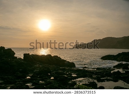 A sunset view featuring rock formations at Menganti Beach, Central Java.