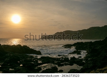 A sunset view featuring rock formations at Menganti Beach, Central Java.