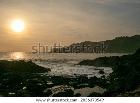 A sunset view featuring rock formations at Menganti Beach, Central Java.