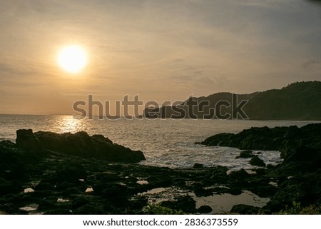 A sunset view featuring rock formations at Menganti Beach, Central Java.