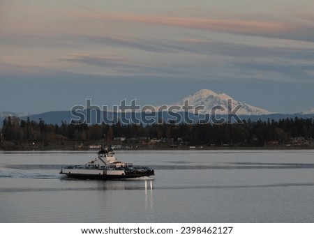 Sunset View of a Ferry Boat Crossing Hale Pass to Lummi Island. With Mt. Baker in the background this small ferry carries commuters who work in Bellingham, Washington. 