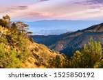 Sunset view of hills and valleys in the Santa Cruz mountains; South Clara Valley and Diablo mountain range visible in the background