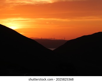 A sunset view from the Isle of Arran,Scotland. UK. Looking over to the windmills on Kintyre and beyond to the hills of the Isle of Jura 